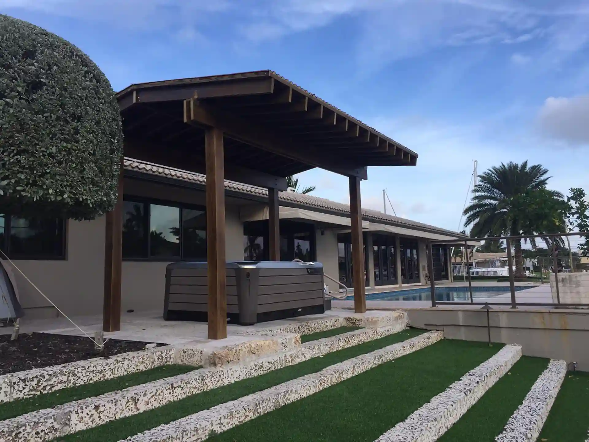 Photo of a patio with a hot tub, patio cover, and steps with artificial turf